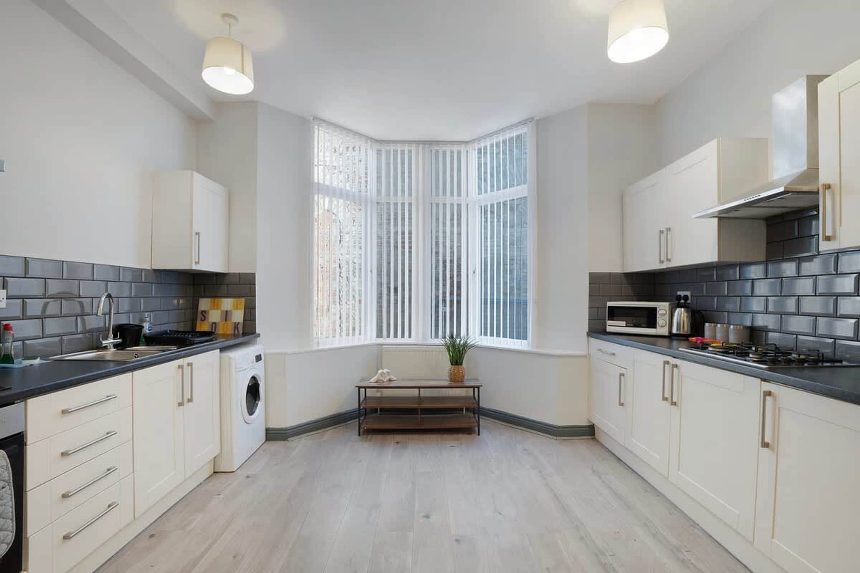 A modern kitchen with a bay window, built-in appliances, and a central island.