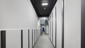 A long, narrow hallway with white walls and a grey floor, leading to a blue door at the end. - Stockton 5BR for Contractors With Free Parking (Stockton-on-Tees)