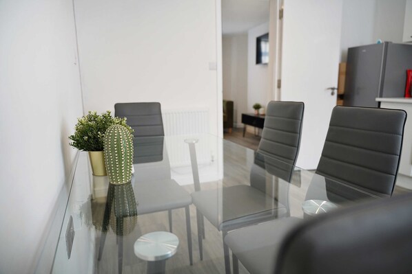 A modern meeting room with a glass table, four black chairs, and a cactus plant. - Contractor Friendly2br Great Wi-fi by Stay With Us (Bishop Auckland)