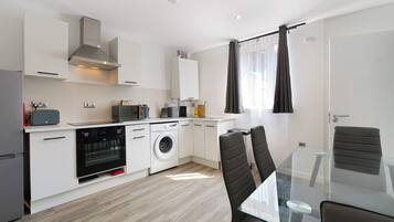 A modern kitchen with a built-in oven, microwave, and washing machine.