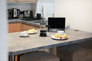 A kitchenette with a coffee maker, a laptop, and croissants on a countertop. - Luxury 1 Bedroom in Hartlepool With Wifi (Hartlepool)