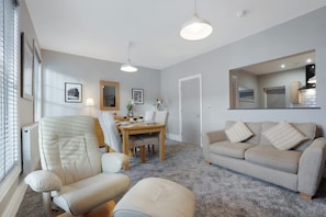 A modern living room with a sofa, armchair, dining table, and a large mirror. - Luxury 1 Bedroom in Hartlepool With Wifi (Hartlepool)