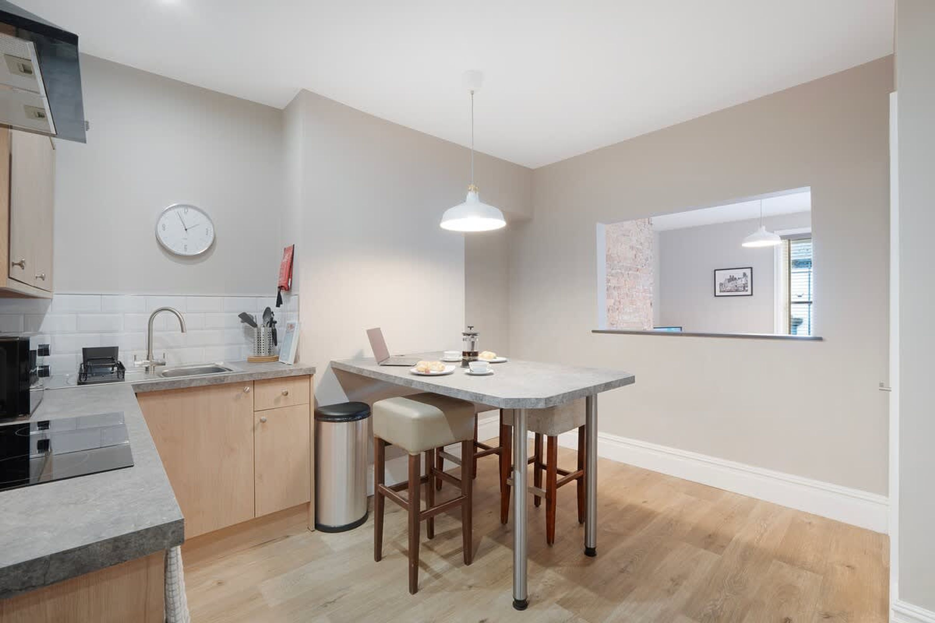 A modern kitchen with a central island, a sink, and a clock on the wall.