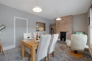 A dining area with a wooden table and chairs, a fireplace, and a brick wall. - Luxury 1 Bedroom in Hartlepool With Wifi (Hartlepool)