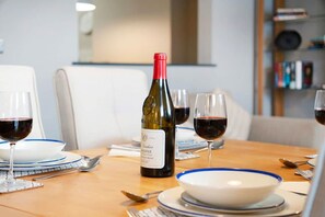 A dining table set with wine glasses, a bottle of wine, and plates with blue rims. - Luxury 1 Bedroom in Hartlepool With Wifi (Hartlepool)