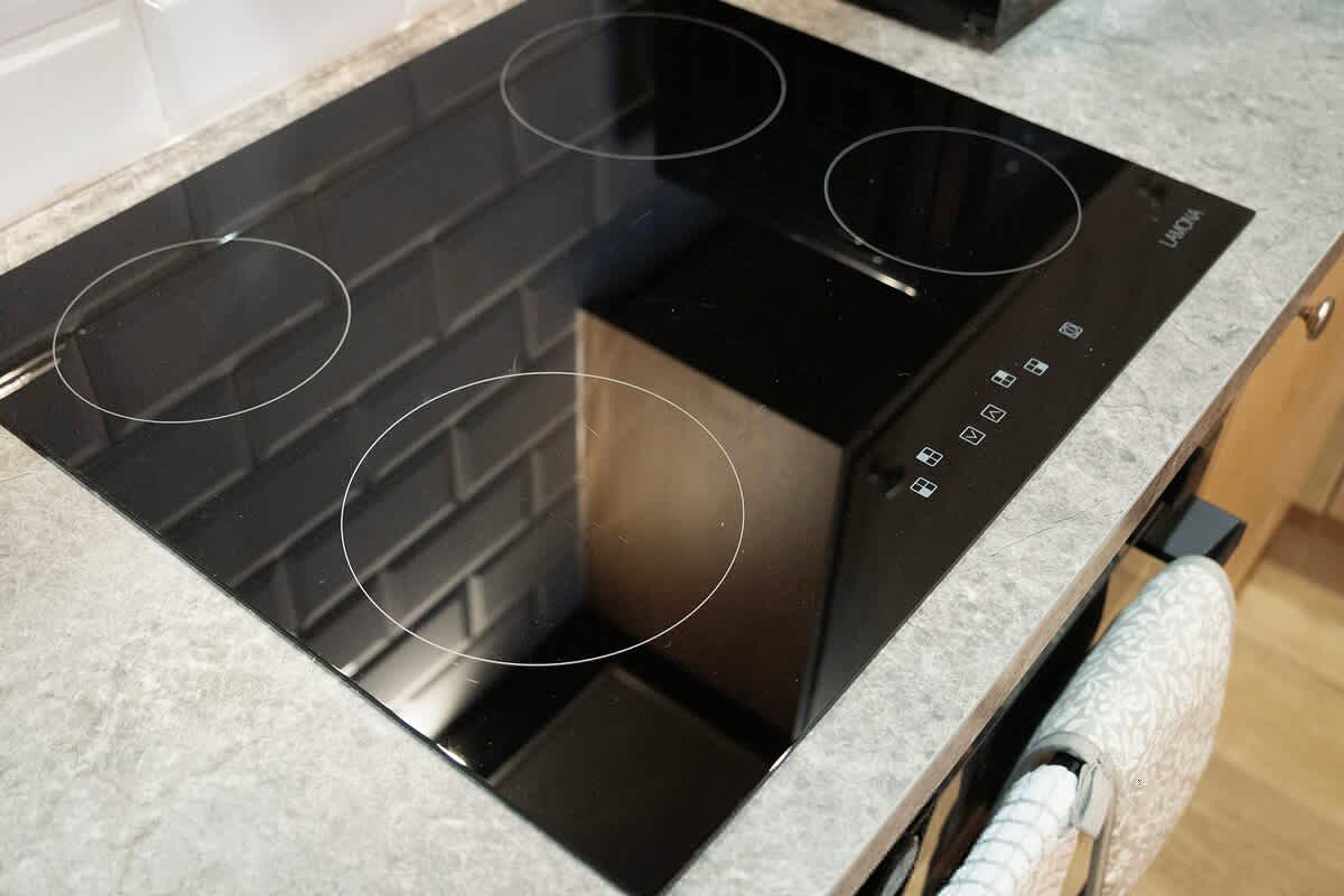 A black induction cooktop with four burners and a control panel with various buttons.