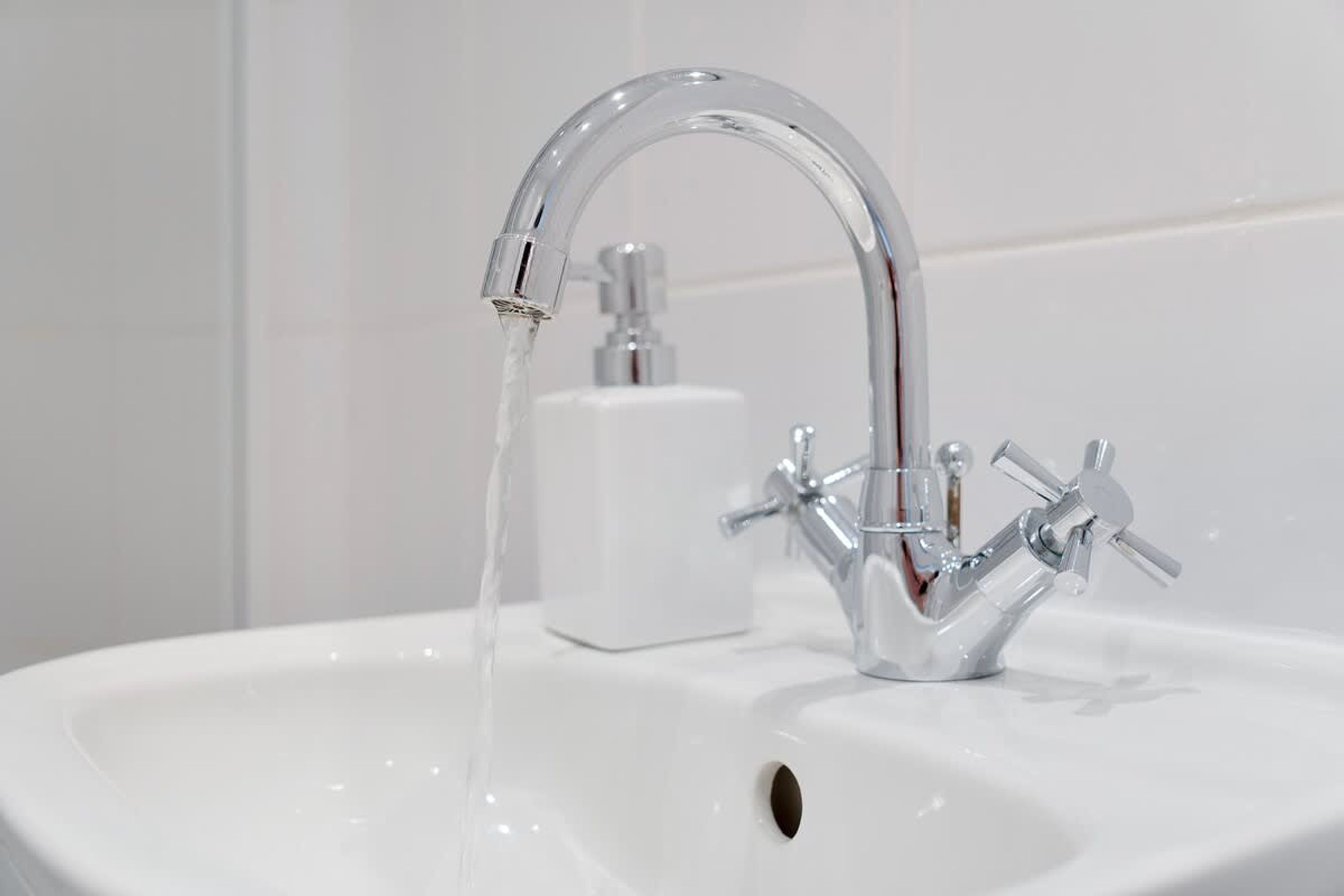 Un lavabo de bany amb un aire de metall cromat i un dosificador de sabó.