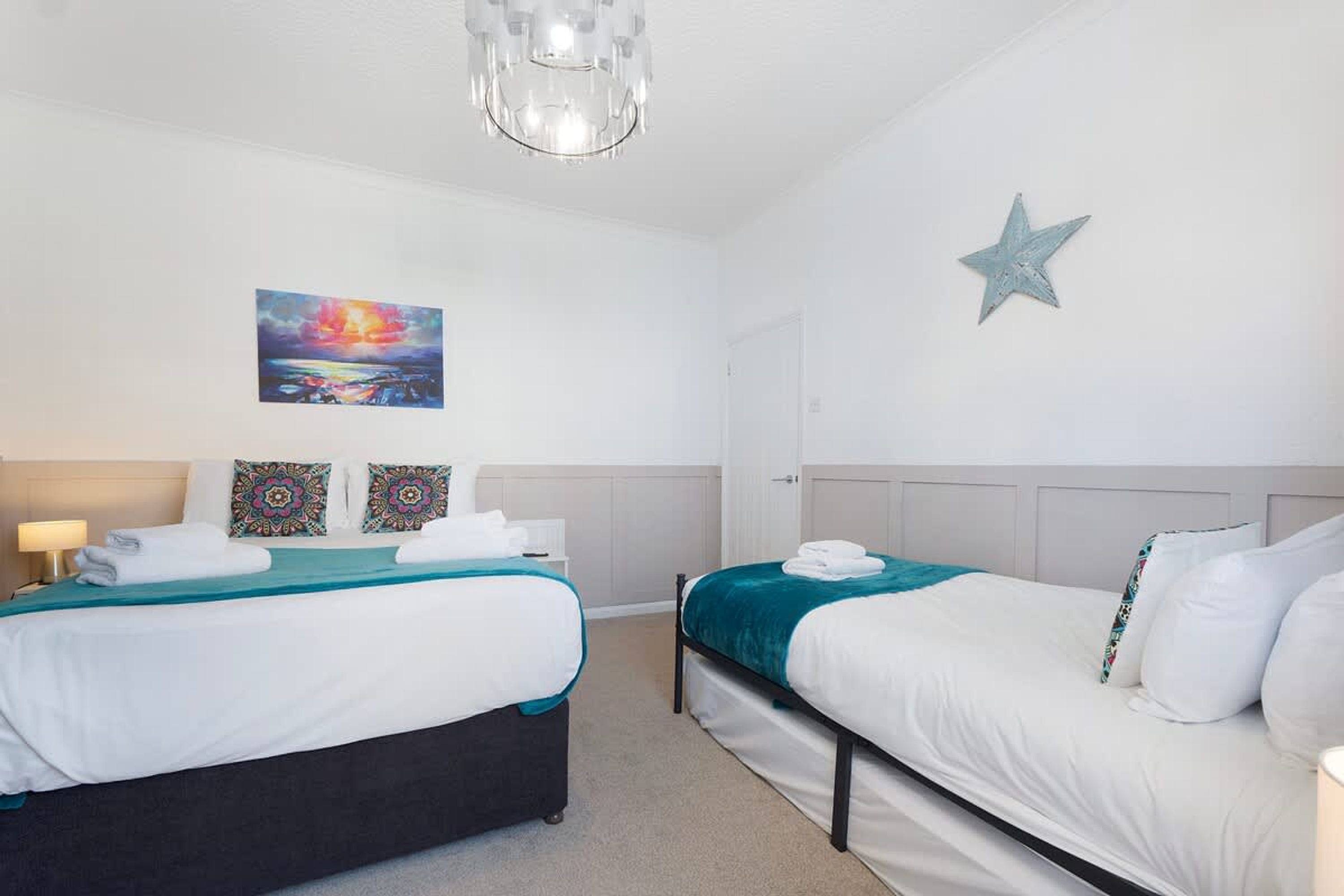 Quarto de hotel com duas camas, um quadro, uma decoração de estrela e um abajur.