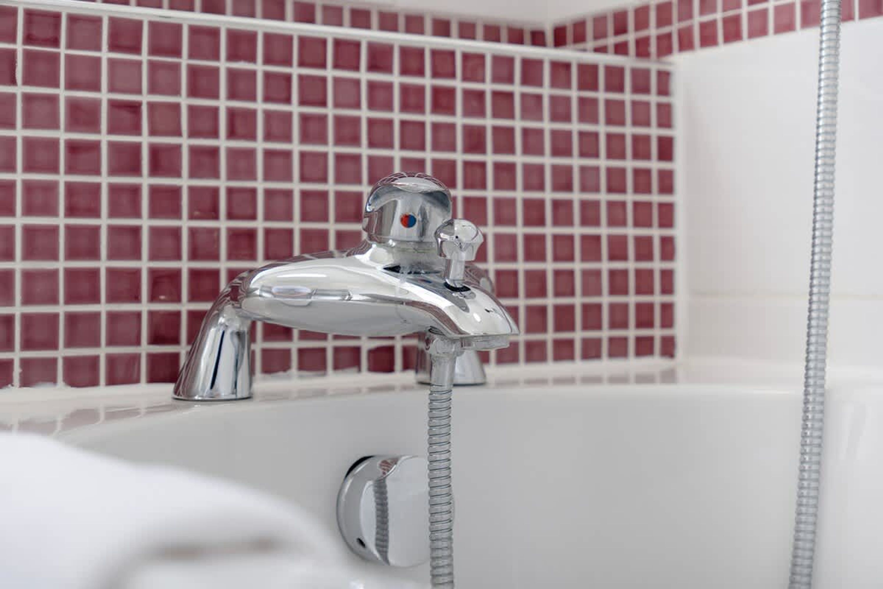 A bathroom with a chrome faucet and a showerhead.