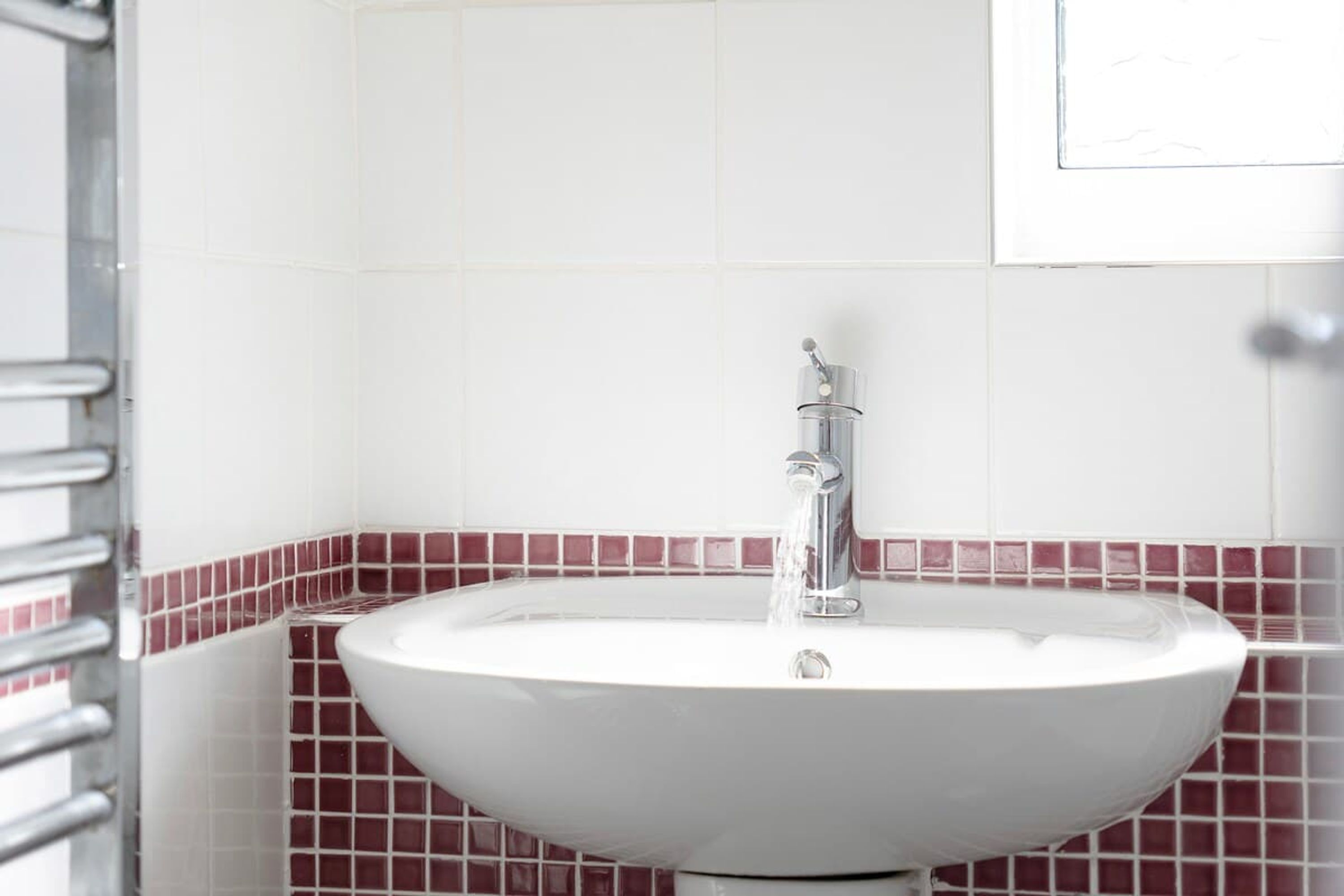 A bathroom with a white sink, chrome faucet, and red-tiled walls.