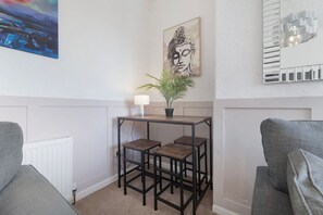 A corner room with a radiator, a table with a lamp and a plant, two chairs, and a wall-mounted mirror. - Stylish 3BR Stay Sleeps 9 by Stay With Us (Trimdon Station)