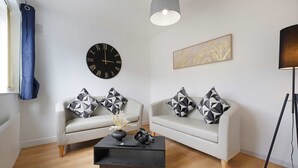 A modern living room with two sofas, a coffee table, a wall clock, and a pendant light. - Spacious 4BR Home Sleeps 8 by Stay With Us (Consett)