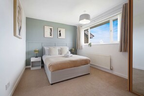 A bedroom with a bed, nightstands, a radiator, a window with curtains, and wall art. - Spacious 4BR Home Sleeps 8 by Stay With Us (Consett)