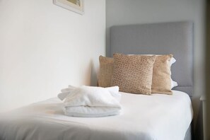 Un lit bien fait, avec des oreillers et une serviette pliée.