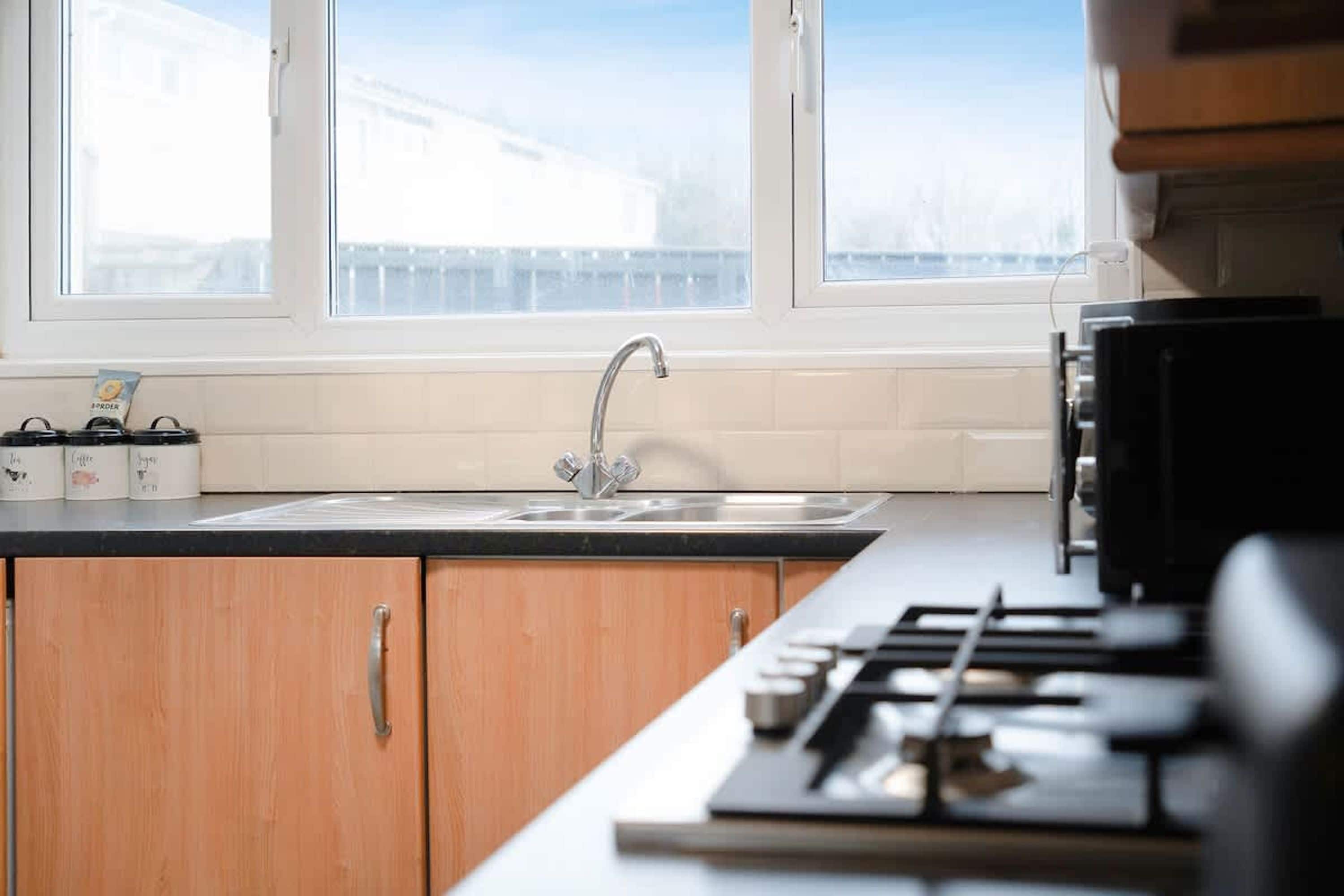 A kitchen with a window, a sink, cabinets, and a stove.