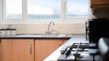 A kitchen with a window, a sink, cabinets, and a stove.