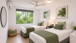 A hotel room with two beds, a large window, a ceiling fan, and a wall-mounted air conditioner. - Modern Family Retreat Townsville• Walk to Mater Hospital • Parking (Pimlico)