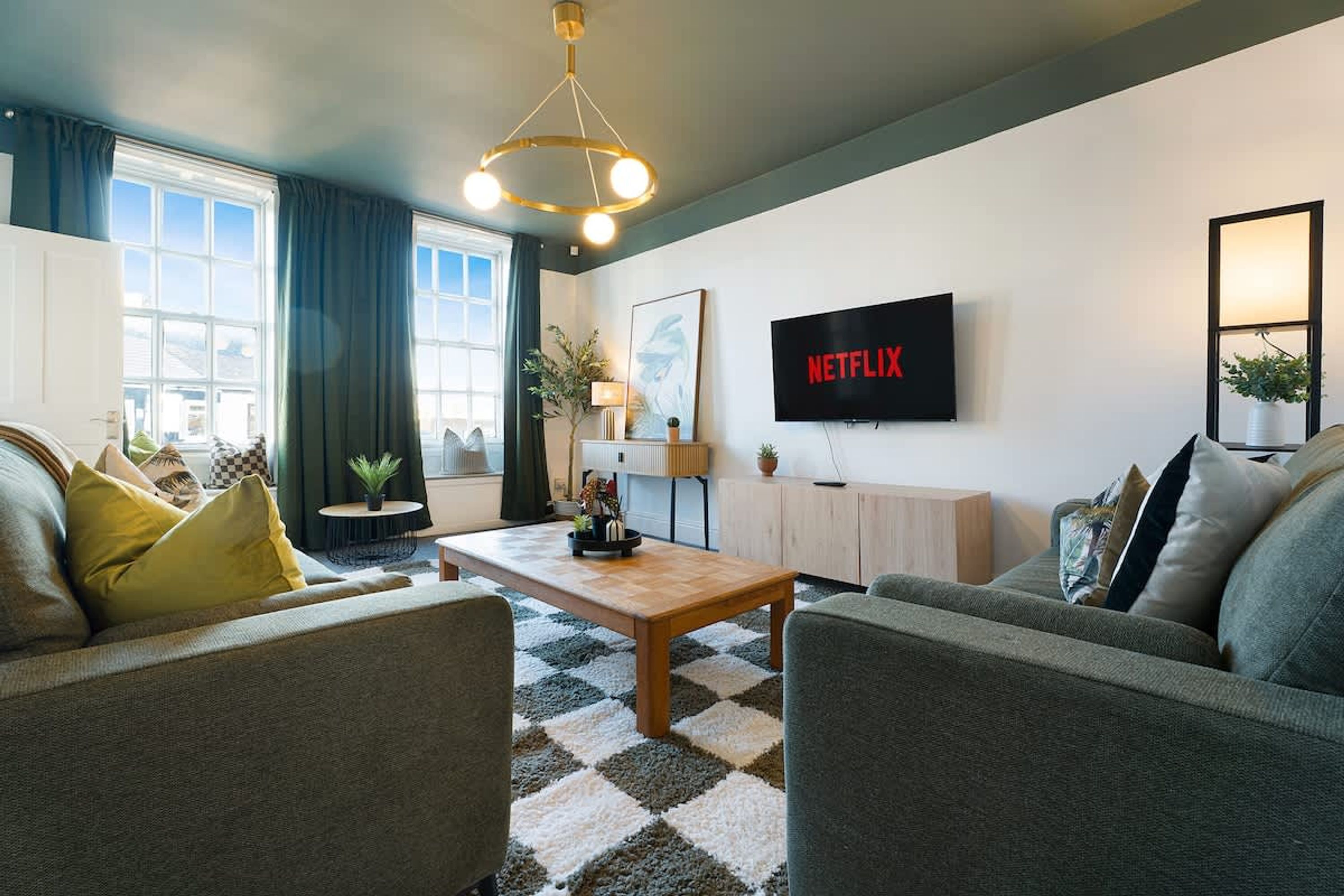 A modern living room with a sofa, coffee table, and a flat-screen TV mounted on the wall.