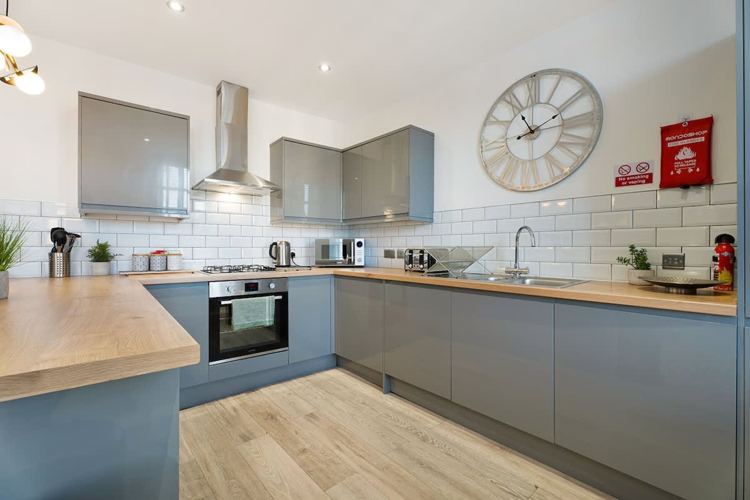 Een moderne keuken met een centraal eiland, roestvrijstalen apparatuur en een klok aan de muur.