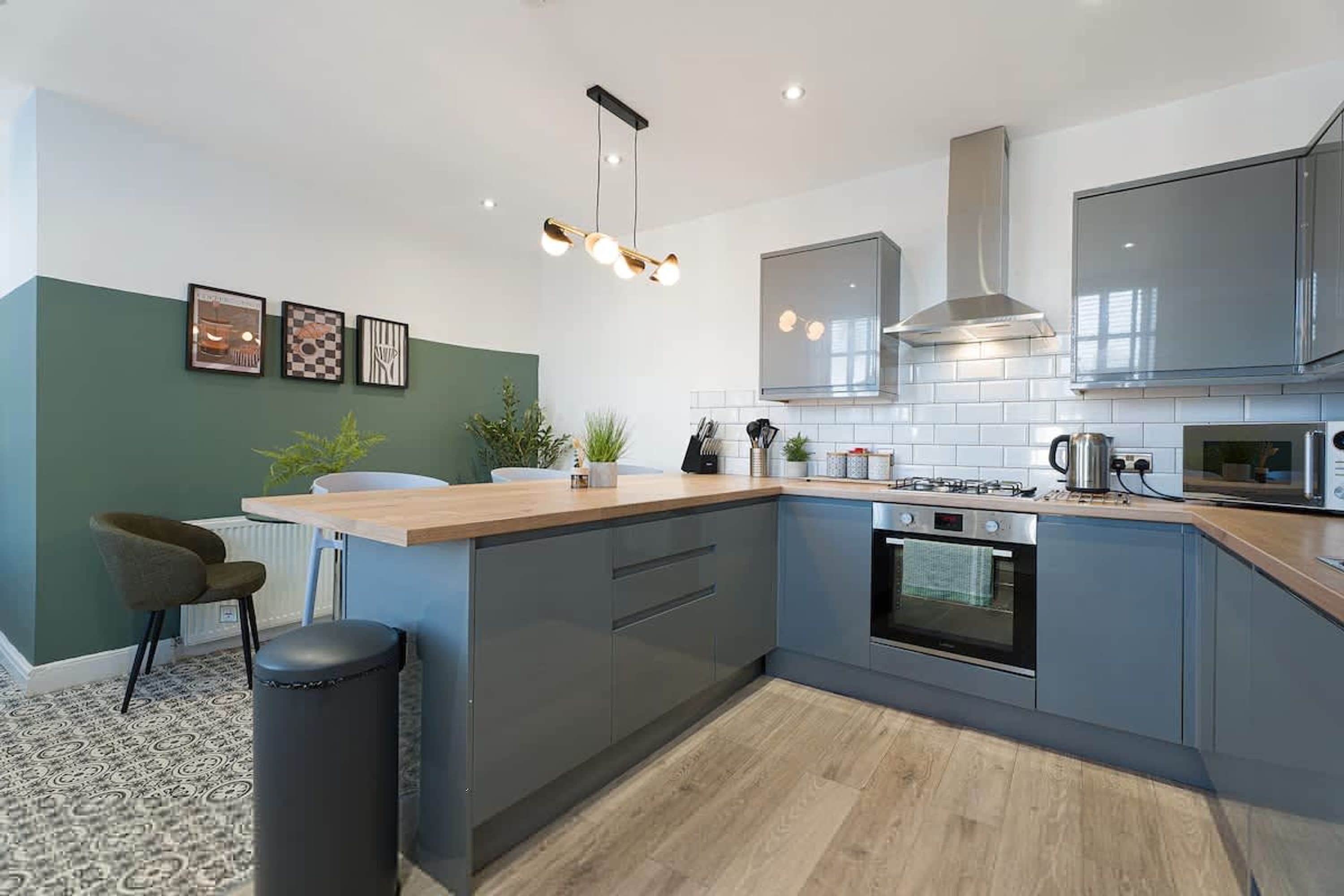 Una cucina moderna con isola centrale, elettrodomestici integrati e lampada a sospensione.