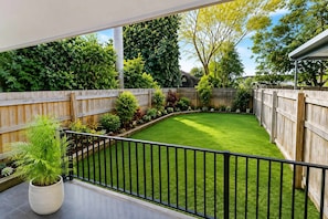 Ein Garten mit Holzzaun, gepflegtem Rasen und einem Blumentopf.