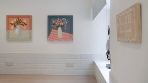 A kitchen with white subway tiles, a wooden countertop, and two wall-mounted paintings. - Spacious 6BR Sleeps 12 With Parking (South Shields)