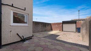 A courtyard with a hexagonal tiled floor, a closed garage door, and a window with a view of a brick wall. - Spacious 6BR Sleeps 12 With Parking (South Shields)