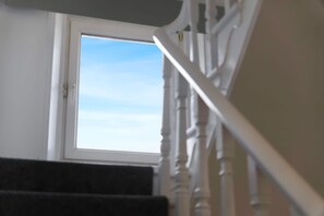 Un escalier avec une rampe blanche et une fenêtre en haut.