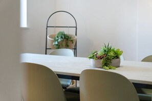 Une table à manger avec des chaises, une plante en pot et une suspension décorative ornée de plantes vertes.