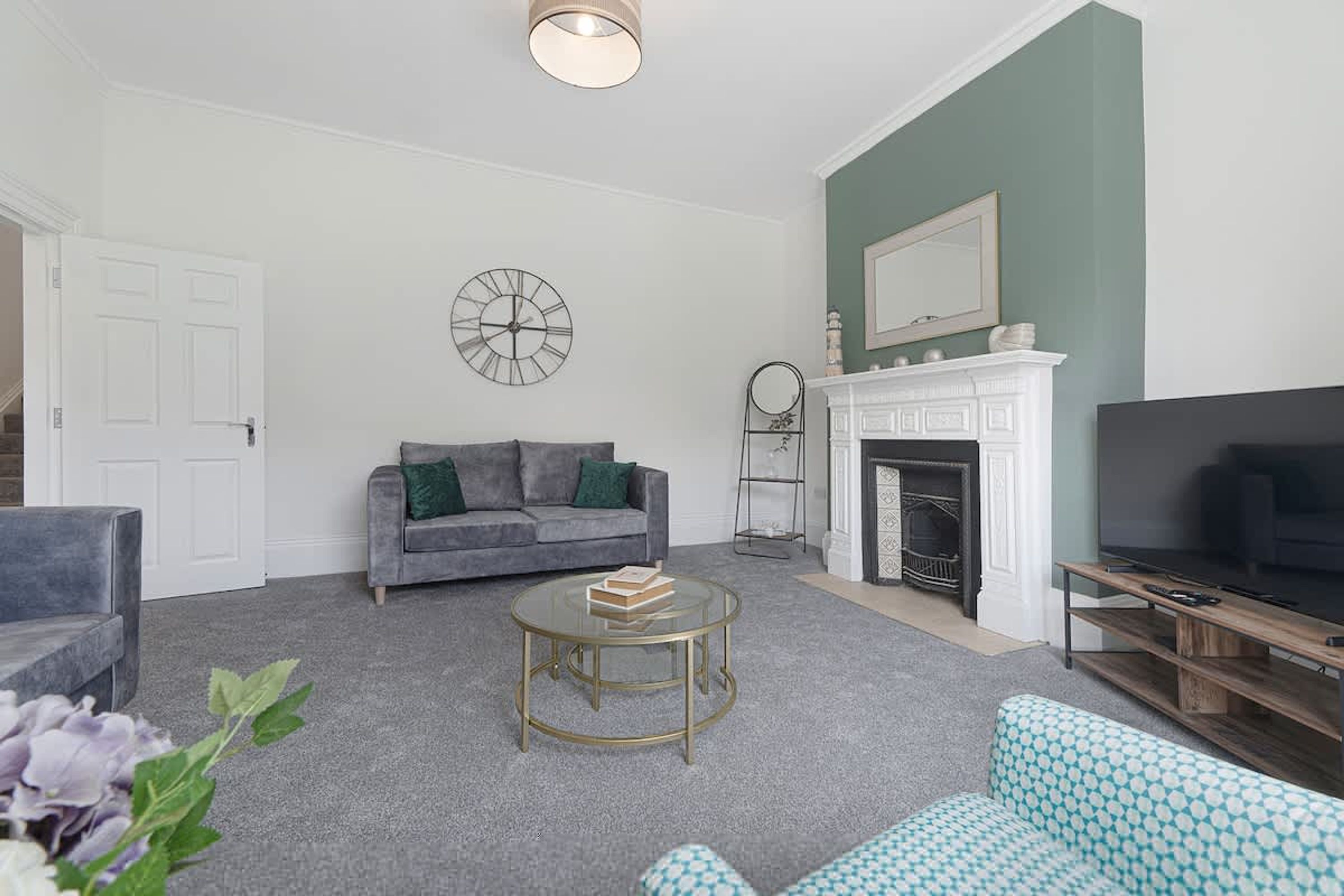 A living room with a grey sofa, a round coffee table, a fireplace, and a television.