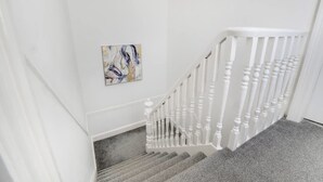 Un escalier avec des balustrades blanches et une plateforme recouverte de moquette.