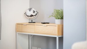 Une pièce avec un bureau en bois, un globe terrestre, une télécommande et une plante en pot.