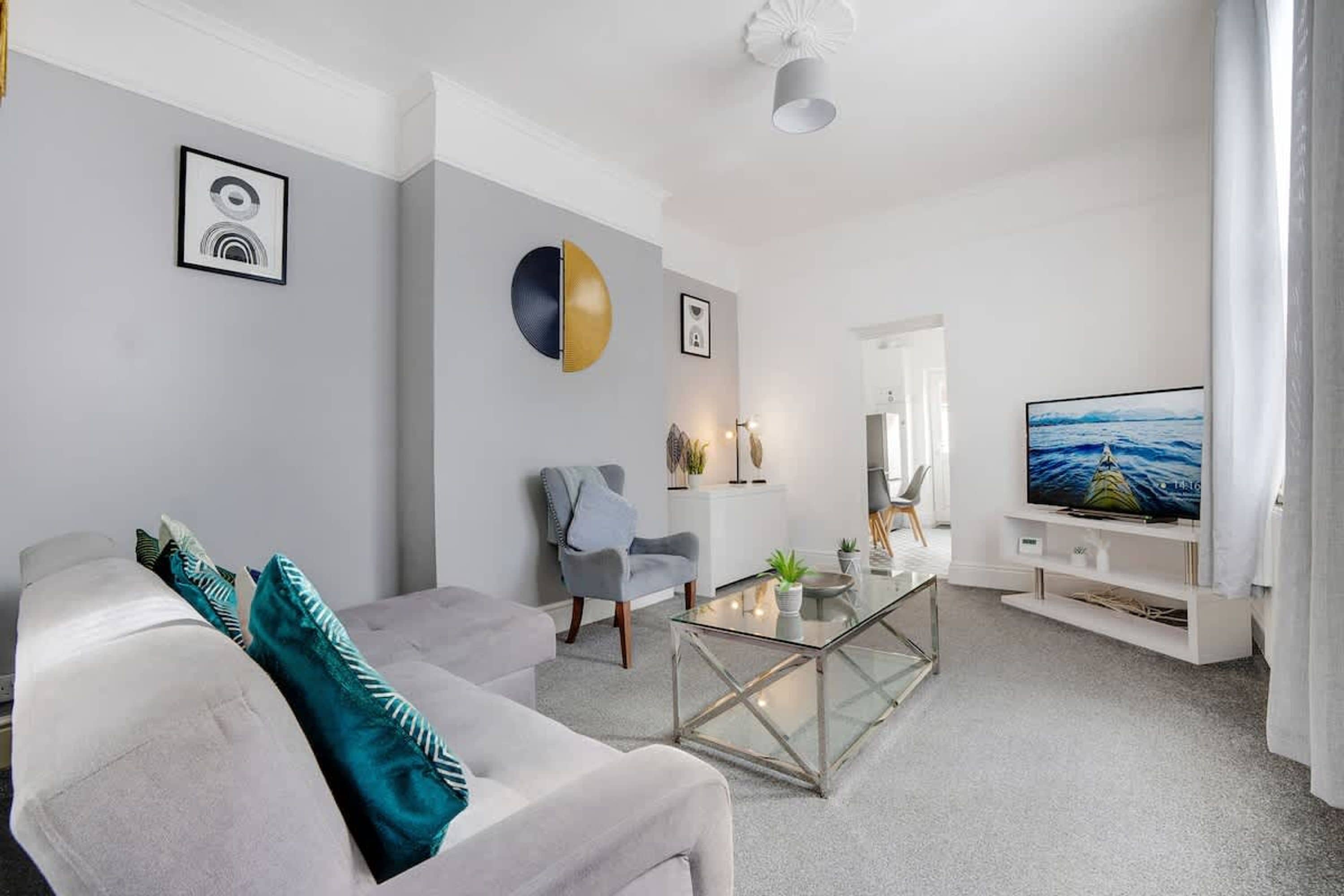A modern living room with a sofa, a coffee table, and a television.