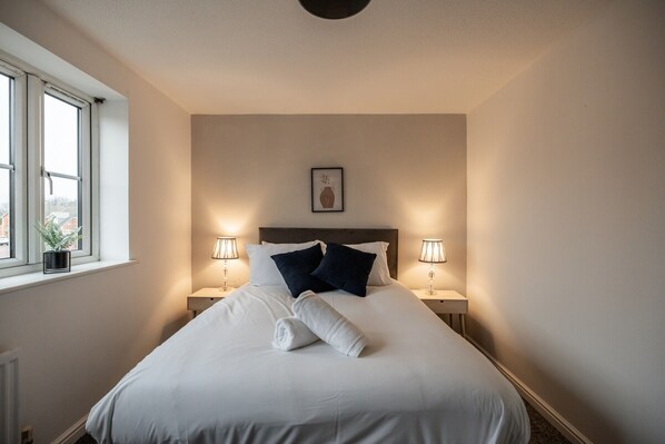 Ein Hotelzimmer mit einem großen Bett, zwei Nachttischlampen, einem Fenster mit Blick und einem gerahmten Bild an der Wand.