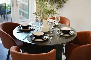 A round dining table set for two with black plates, silverware, and clear wine glasses. - Modern 3BR Brompton Court Wi-fi By Stay With Us (Richmond)