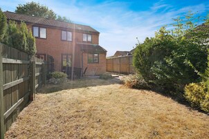 A residential property with a brick house, a wooden fence, and a dry lawn.