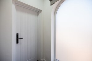Una puerta blanca con un picaporte negro y una ventana a la derecha.