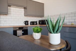 Una cocina moderna con salpicadero de azulejos blancos, encimera de madera y dos macetas.