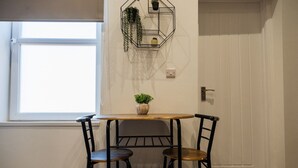 A small dining area with a table and two chairs, a potted plant on the table, and a window with blinds. - The Cockton Quarters Horizon Stays (Bishop Auckland)