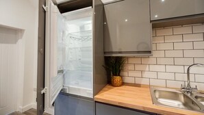 A kitchen with a built-in refrigerator, a wooden countertop, a sink, and a potted plant. - The Cockton Quarters Horizon Stays (Bishop Auckland)