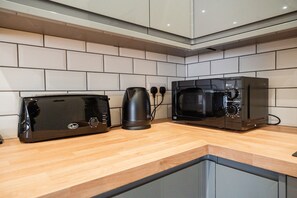 A kitchenette with a toaster, kettle, and microwave on a wooden countertop. - The Cockton Quarters Horizon Stays (Bishop Auckland)