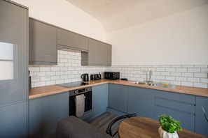 Eine moderne Küche mit grauen Schränken, einer Holzarbeitsplatte und einem eingebauten Backofen.