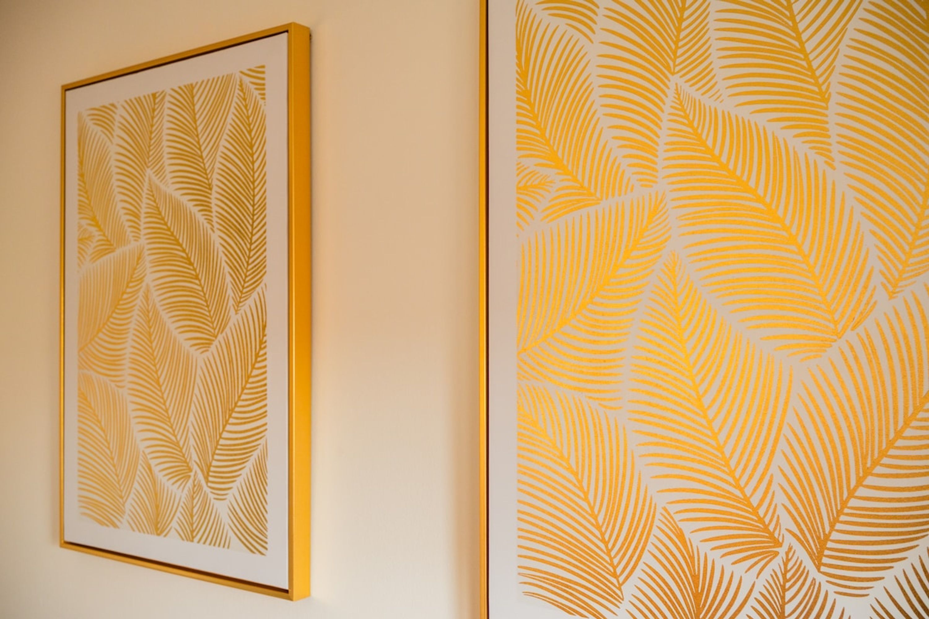 Two framed artworks with leaf patterns on a wall.
