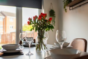 A dining table with a vase of red roses, wine glasses, and plates. - Nightingale House Horizonstays (Stockton-on-Tees)
