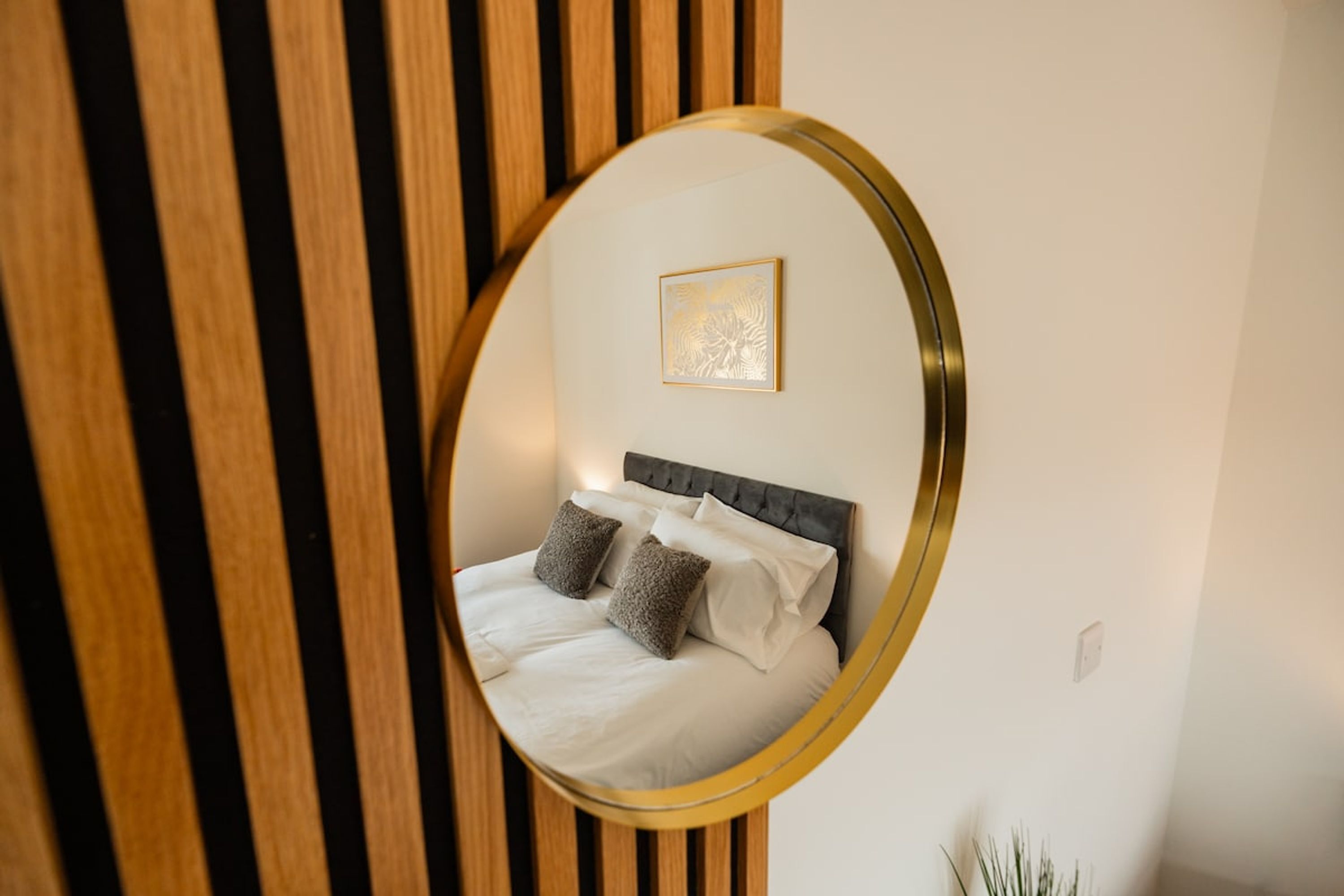 A bedroom with a bed, pillows, a headboard, and a wall-mounted picture.