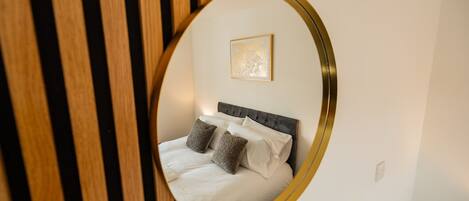 A bedroom with a bed, pillows, a headboard, and a wall-mounted picture.