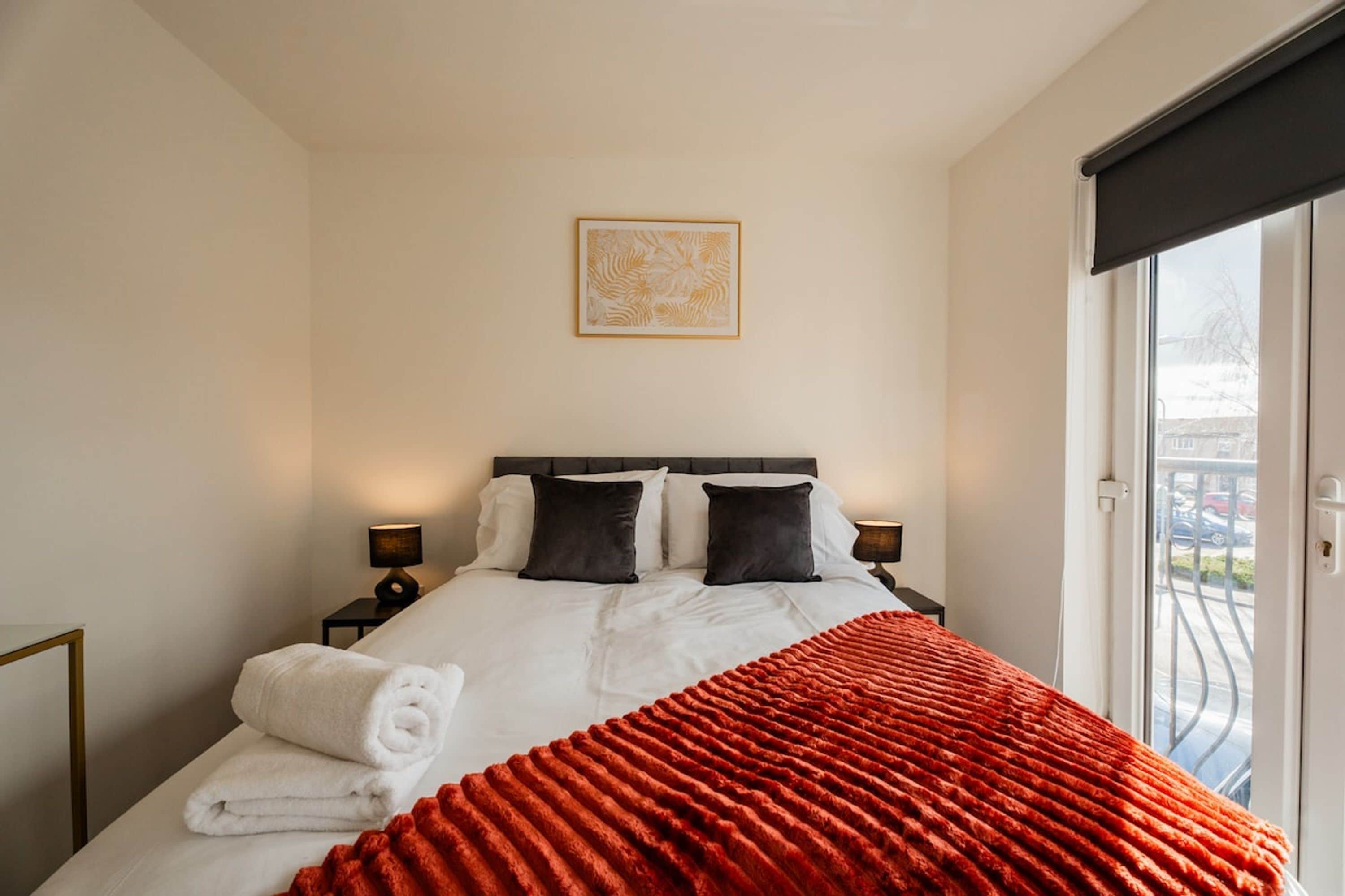 A hotel room with a bed, two bedside tables, a window, and a wall-mounted artwork.
