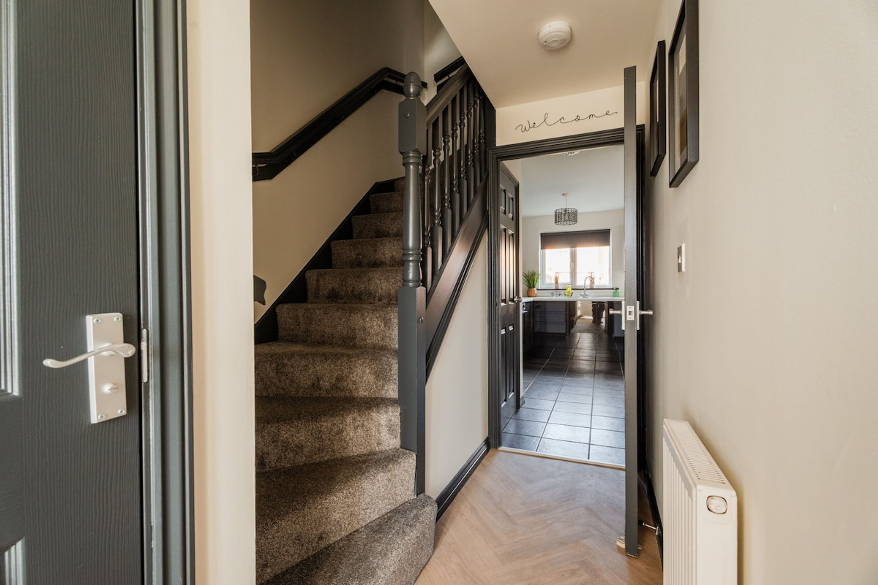 A hallway leading to a kitchen with a staircase.