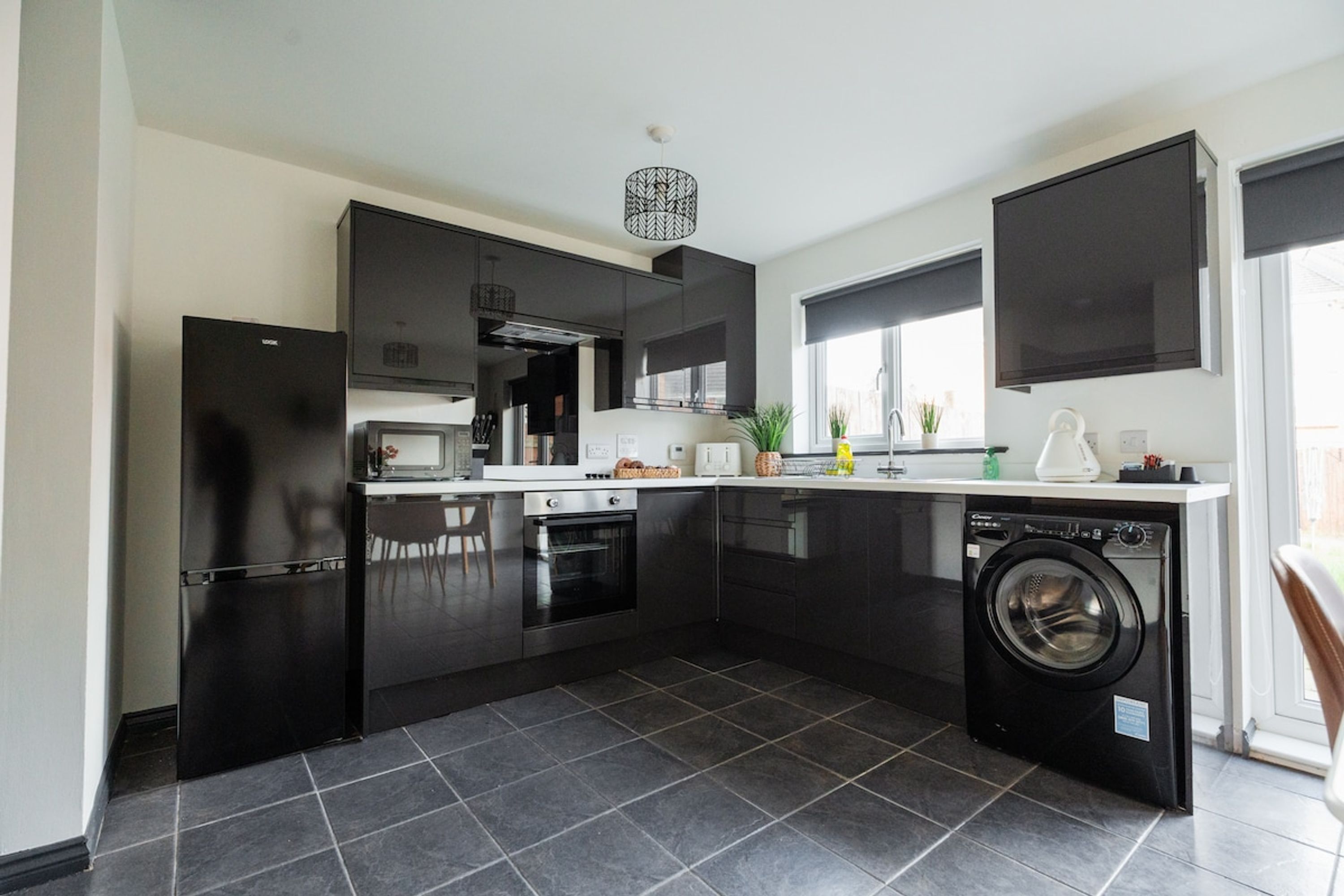 A modern kitchen with black cabinets, a built-in oven, microwave, and dishwasher.
