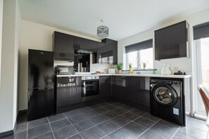 A modern kitchen with black cabinets, a built-in oven, microwave, and dishwasher. - Nightingale House Horizonstays (Stockton-on-Tees)